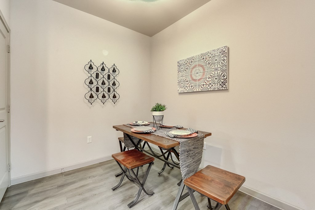 a dining area with a wooden table and chairs and a wall art