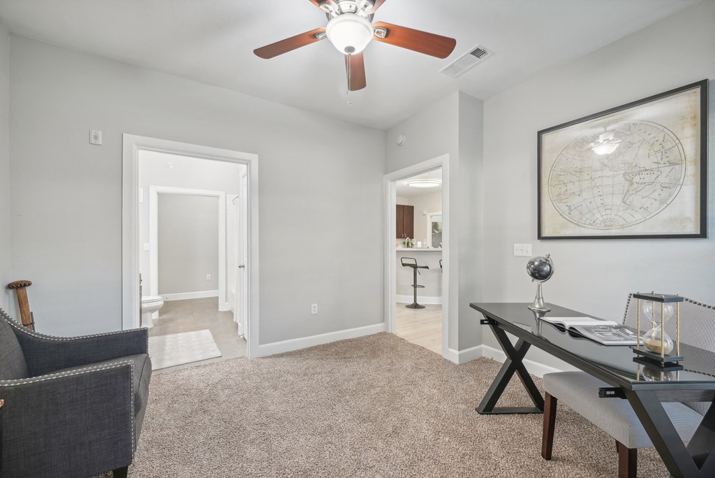 A room with a ceiling fan and a world map on the wall.