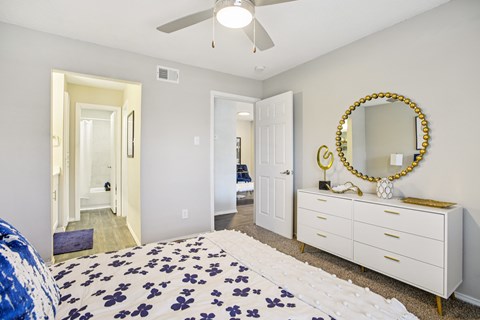 A bedroom with a bed, dresser, mirror and a ceiling fan.