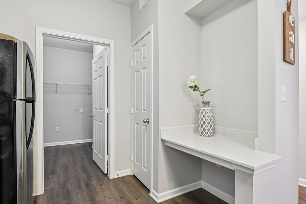 A kitchen with a refrigerator, a bench, and a doorway leading to another room.