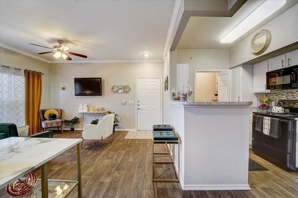 a living room with a kitchen and a ceiling fan