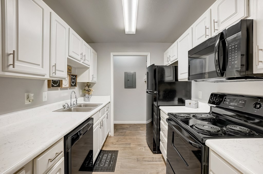 a kitchen with white cabinets and black appliances