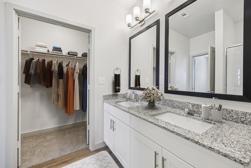 A bathroom with a white vanity and a mirror above it.