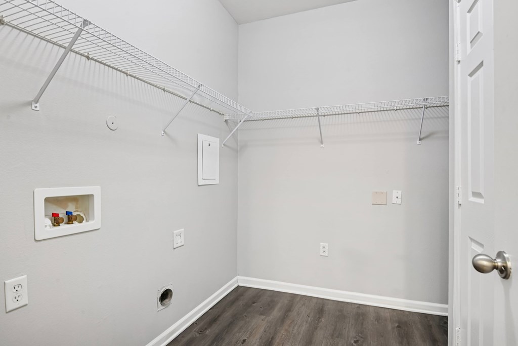 A white room with a door and a shelf with jars on it.