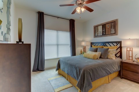 A bedroom with a bed, a dresser, and a ceiling fan.