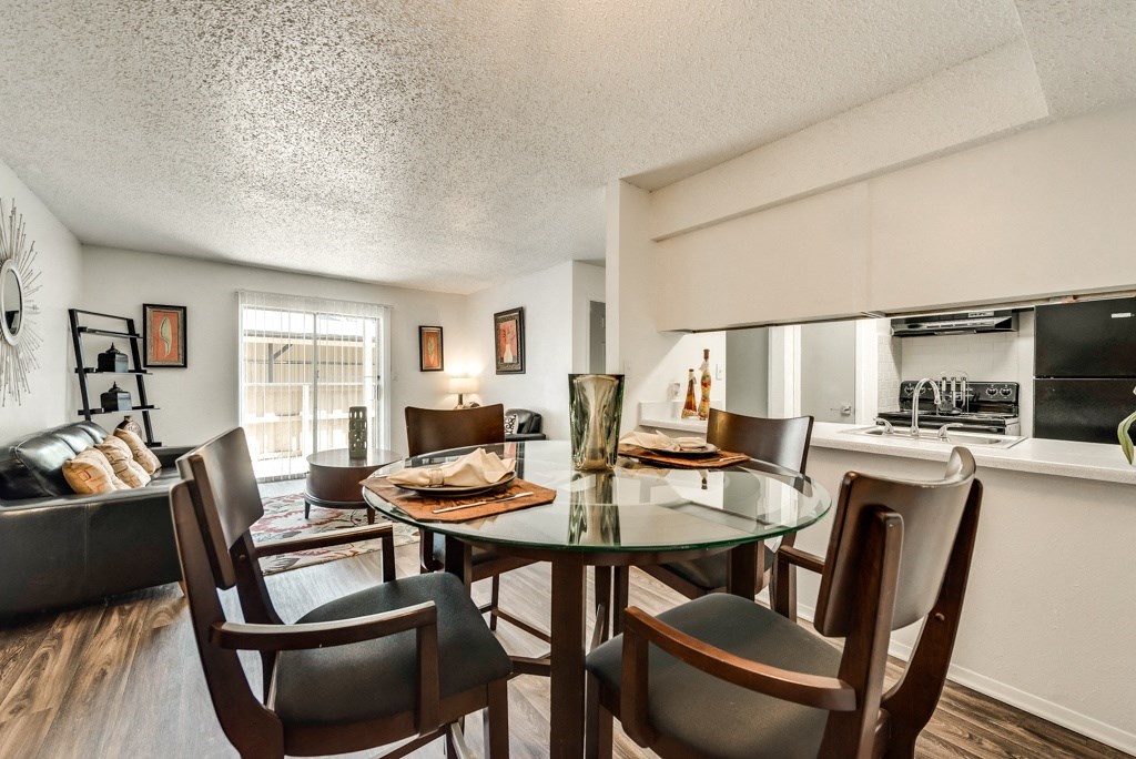 the living room and dining area of an apartment with a table and chairs