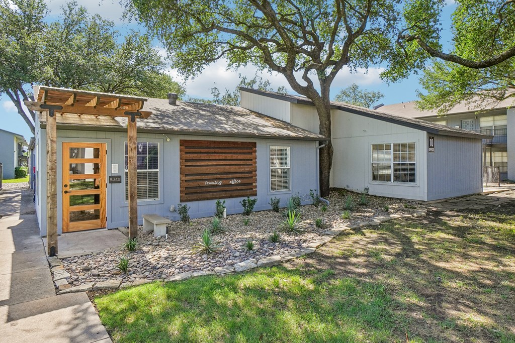A house with a wooden door and a tree in front.