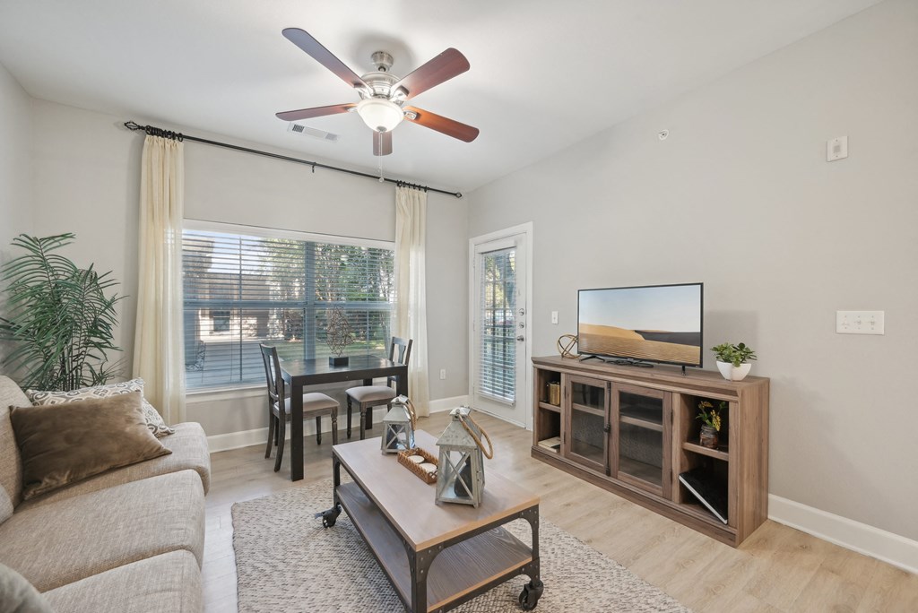 A living room with a couch, a coffee table, a television, and a ceiling fan.