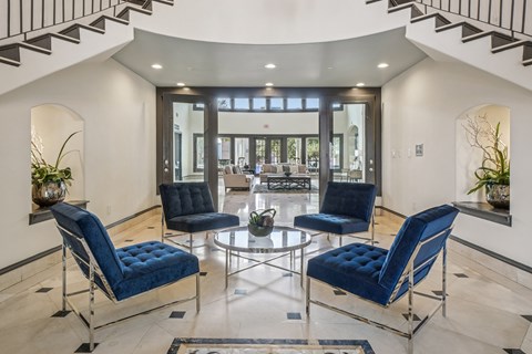 Clubhouse lounge with sofas, fireplace, tall windows, and decorative ceiling beams.