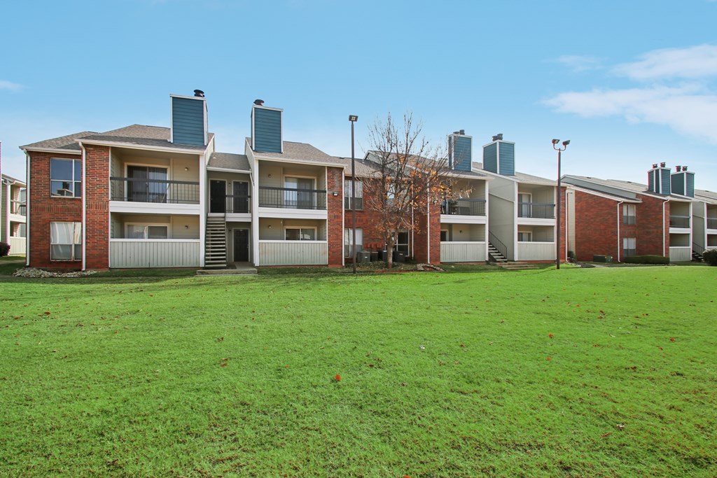 A row of apartment buildings with green grass in the foreground.