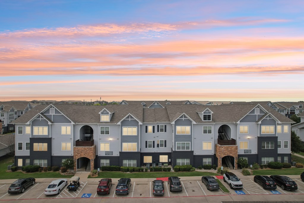 A large apartment complex with a parking lot in front.