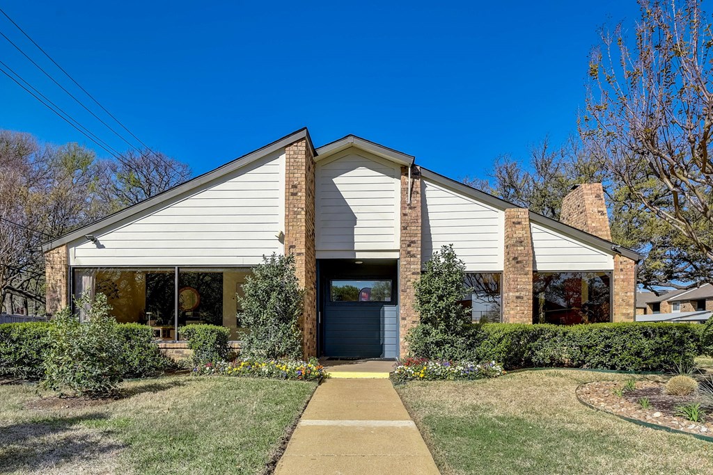 a white and brick house with a sidewalk in front of it
