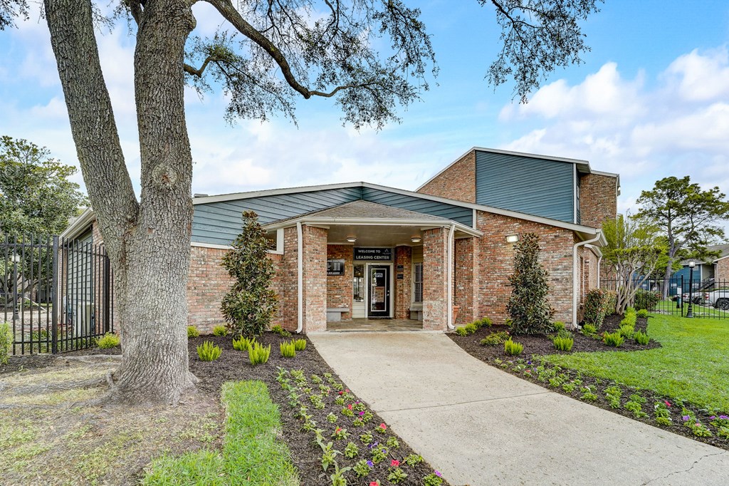 the front of a brick building with a tree and a sidewalk