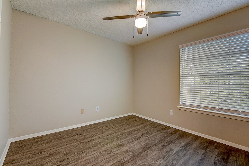 an empty living room with a ceiling fan and a large window