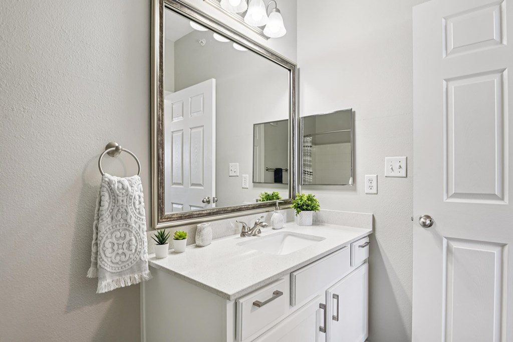 A white bathroom with a mirror, sink, and towel.