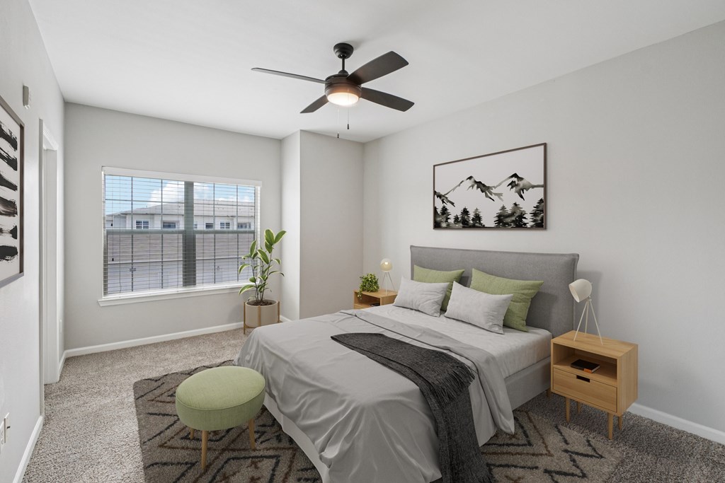 A bedroom with a bed, a chair, and a ceiling fan.