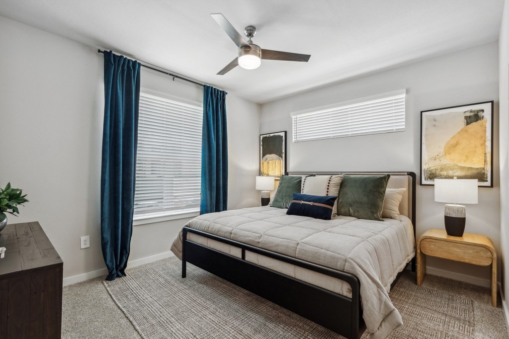A bedroom with a bed, nightstand, and a ceiling fan.