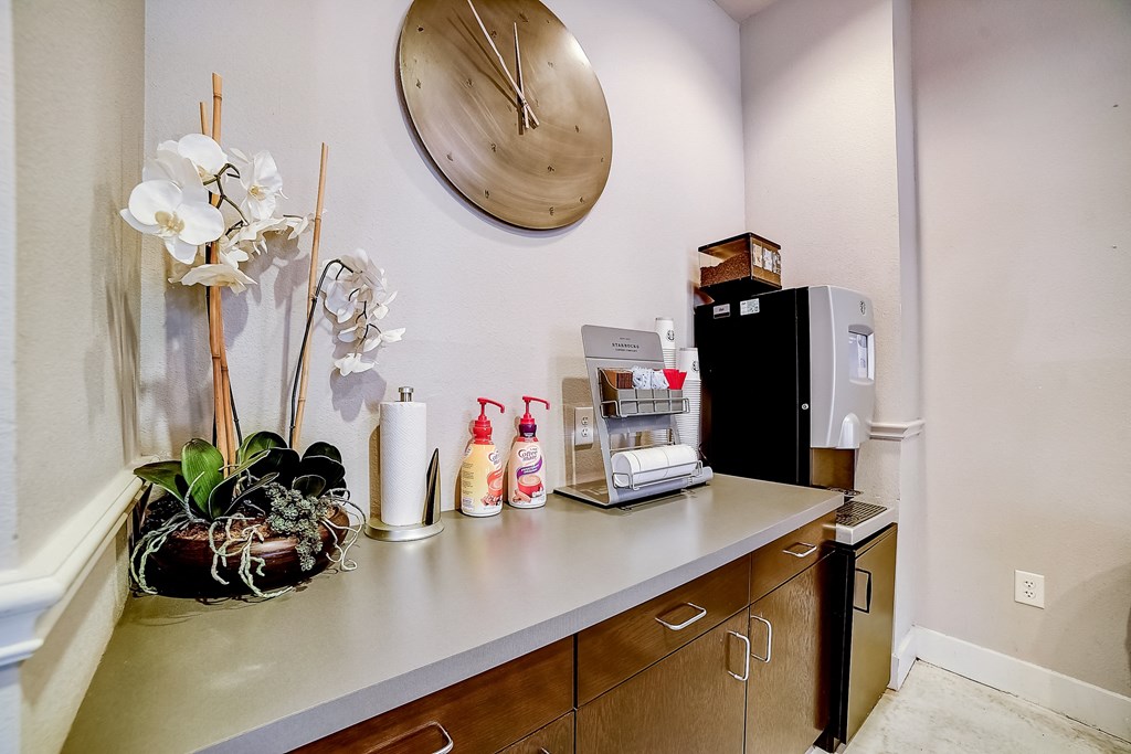 a kitchenette with a coffee machine refrigerator and sink