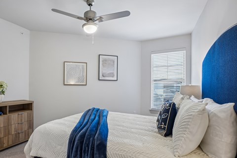 A bedroom with a bed covered in a blue blanket and two pillows.