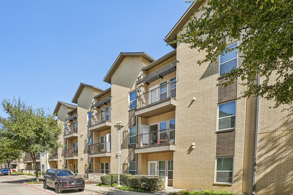 A black car is parked in a red marked spot in front of a building.