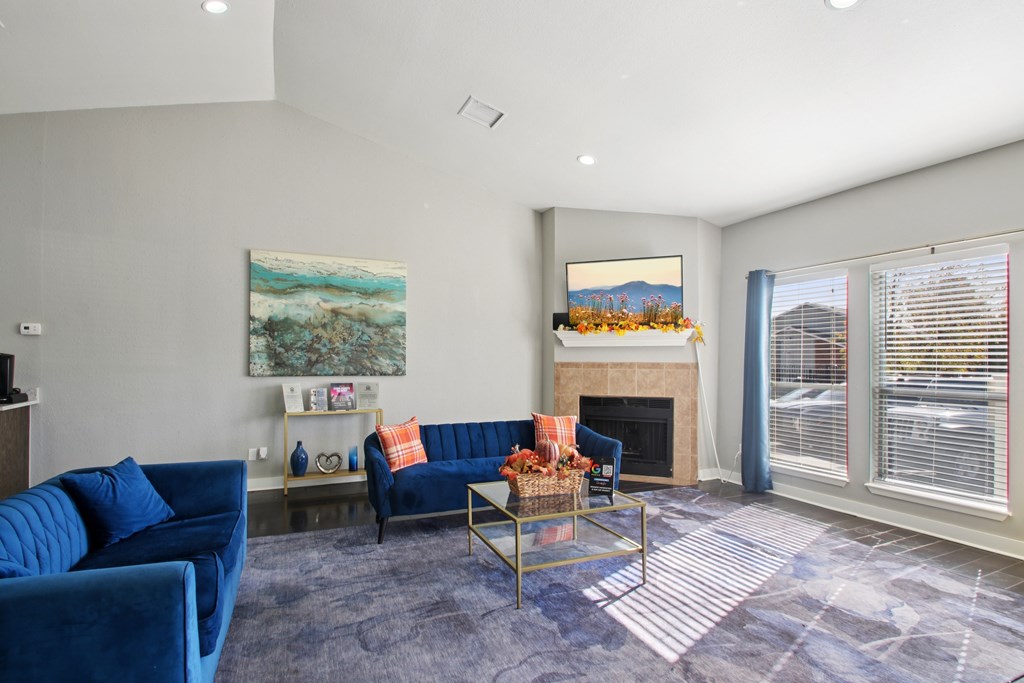 A living room with a blue couch and a painting on the wall.