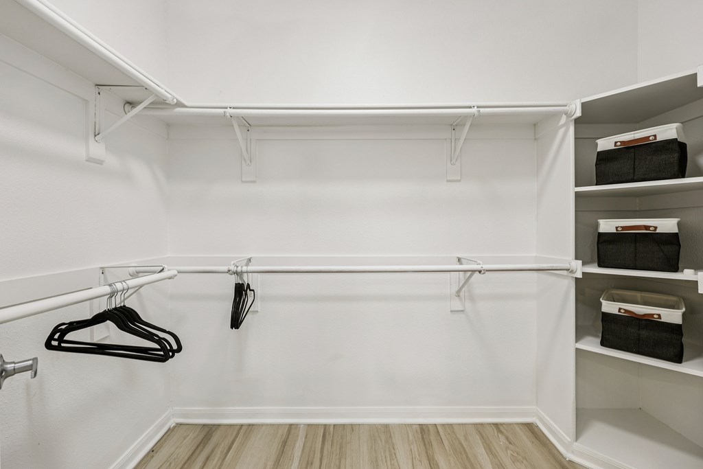 A white closet with clothes hanging and shelves.