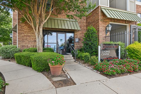 A leasing center sign is in front of a building with a brick facade and a green awning.