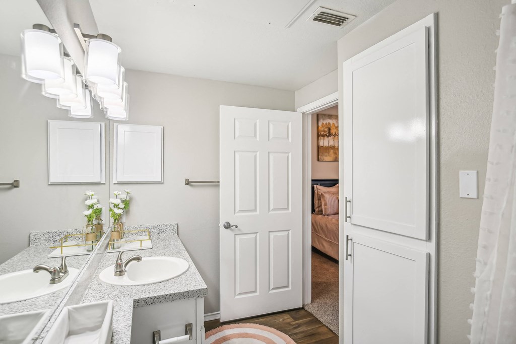 A bathroom with a double sink vanity and a white door.