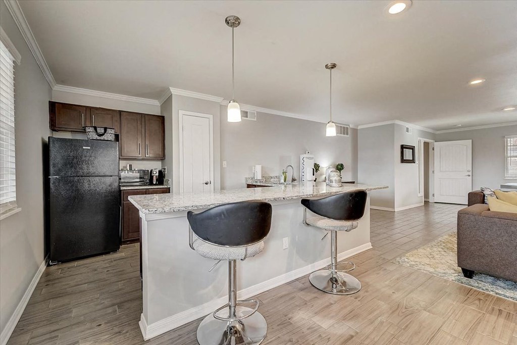a kitchen with a bar and a refrigerator in a living room