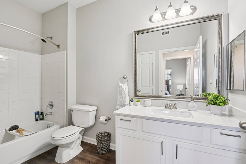A white bathroom with a large mirror and a white bathtub.