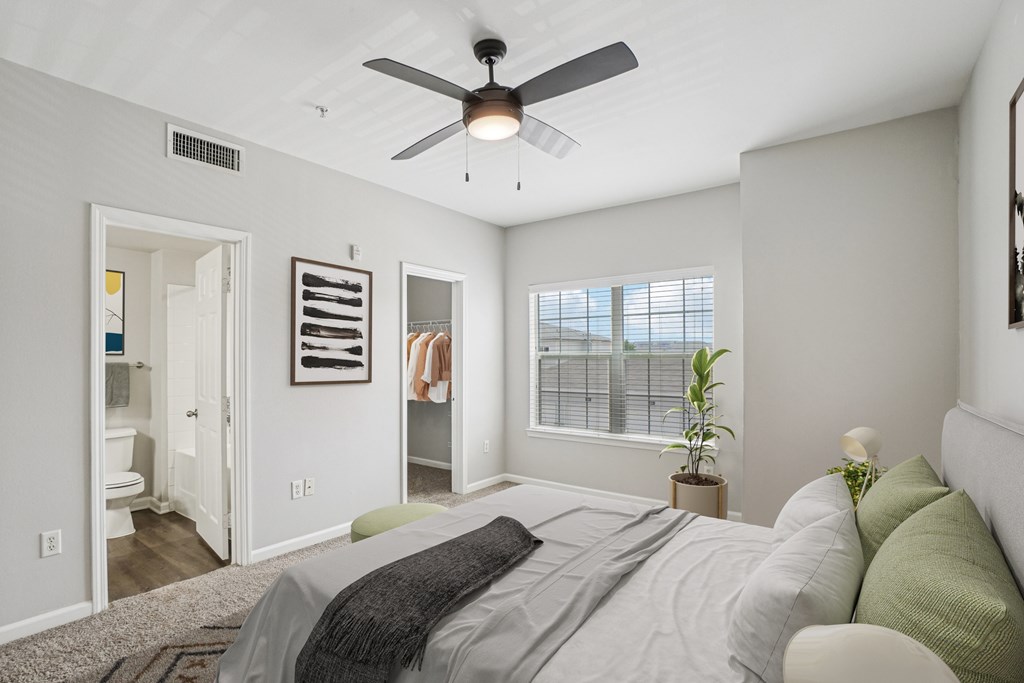 A bedroom with a bed, a ceiling fan, and a window with blinds.