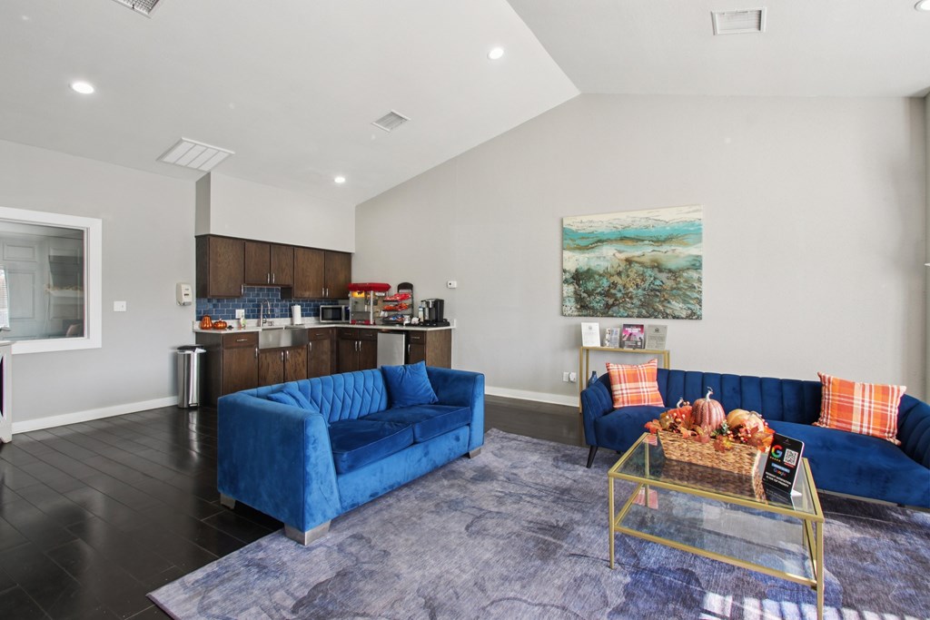 A living room with a blue couch and a painting on the wall.