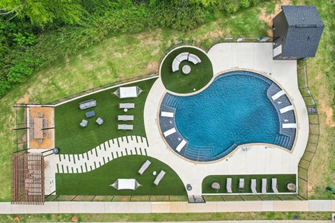 An aerial view of a swimming pool surrounded by a grassy area and a building.