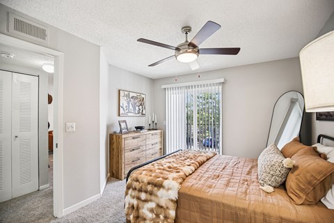 A bedroom with a bed, dresser, and a ceiling fan.