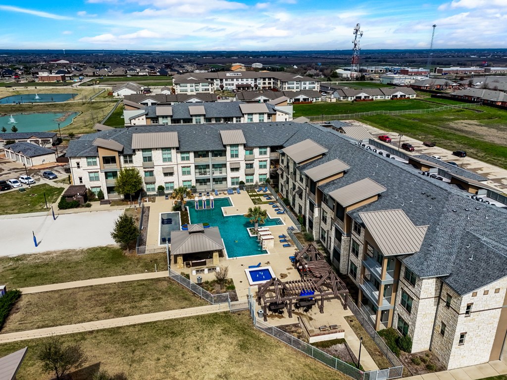 an aerial view of a building with a pool and other buildings