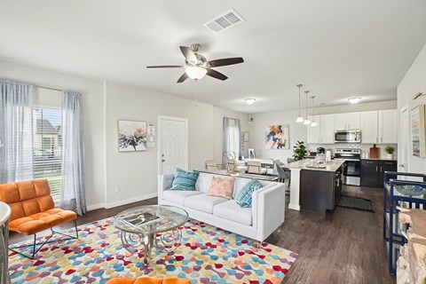 A living room with a white couch and a colorful rug.