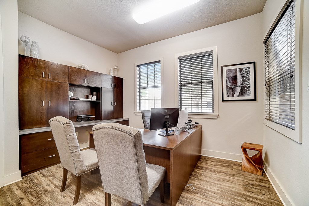 a desk with two chairs and a computer monitor