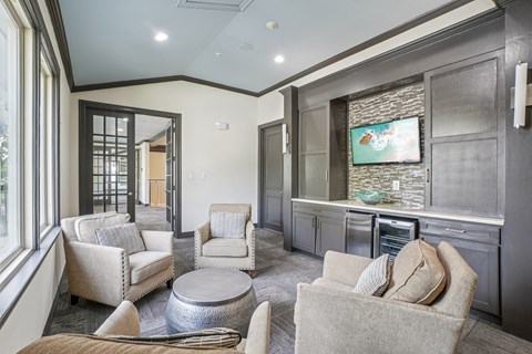 A living room with a grey couch and a television on the wall.