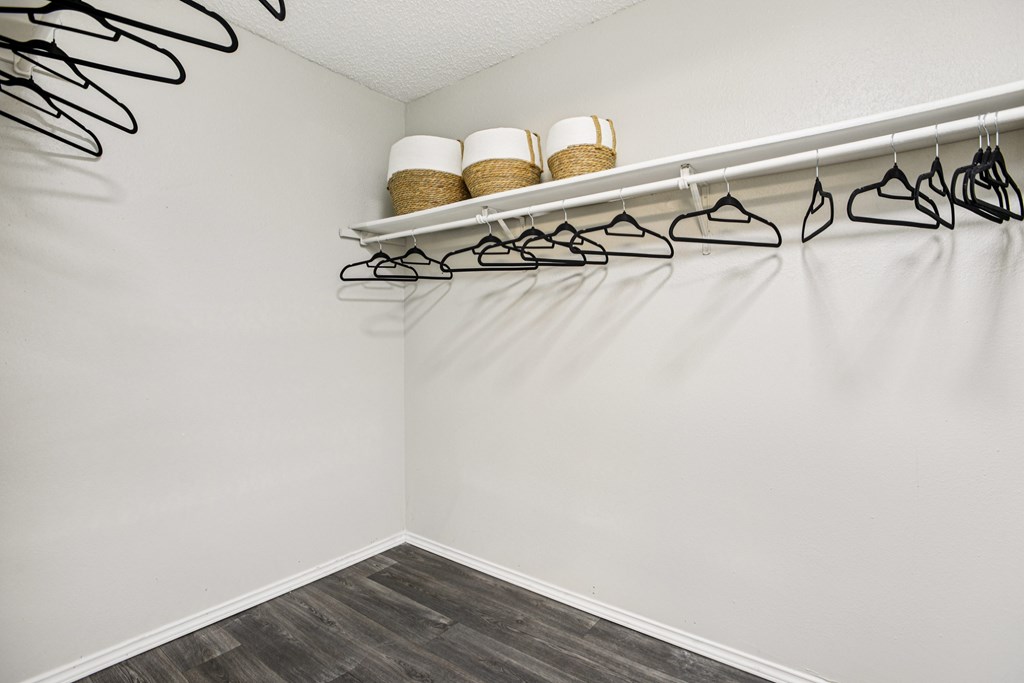 A white closet with two shelves and hangers.