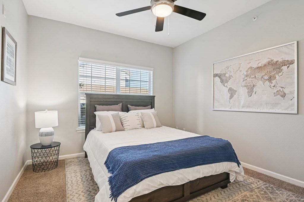 A bedroom with a bed, a ceiling fan, and a world map on the wall.