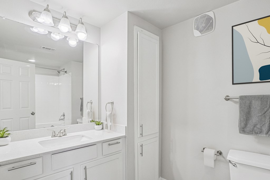 A bathroom with a white sink and a white toilet.