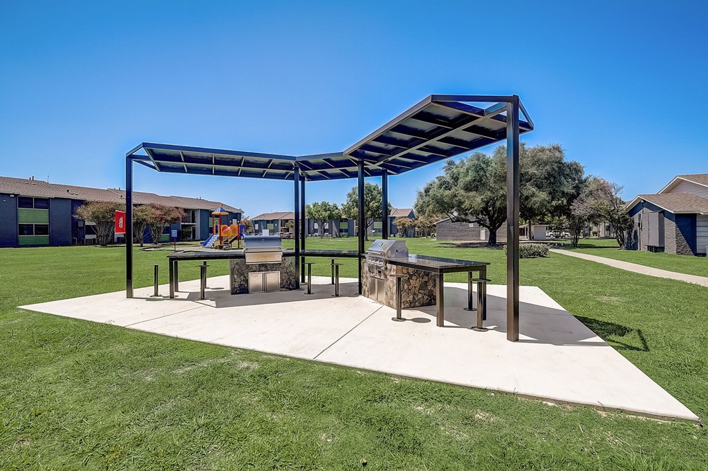 a picnic shelter with a firepit at the whispering winds apartments in pearland, tx