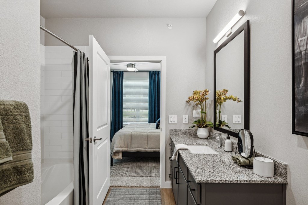 A bathroom with a bed in the background.