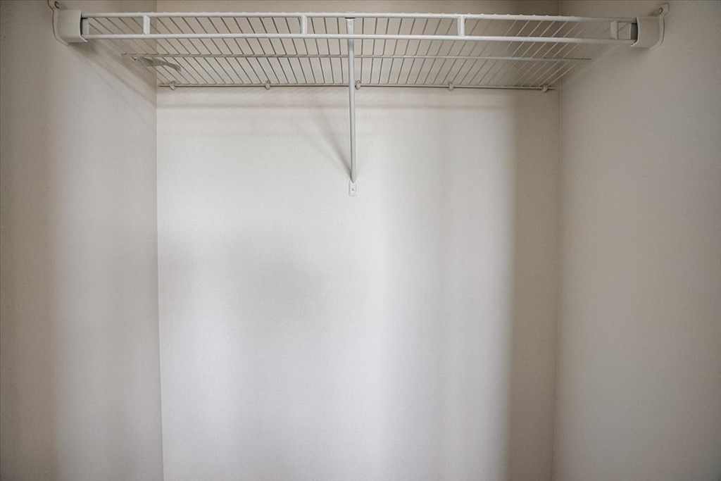 a walk in closet with a white rack on top of it