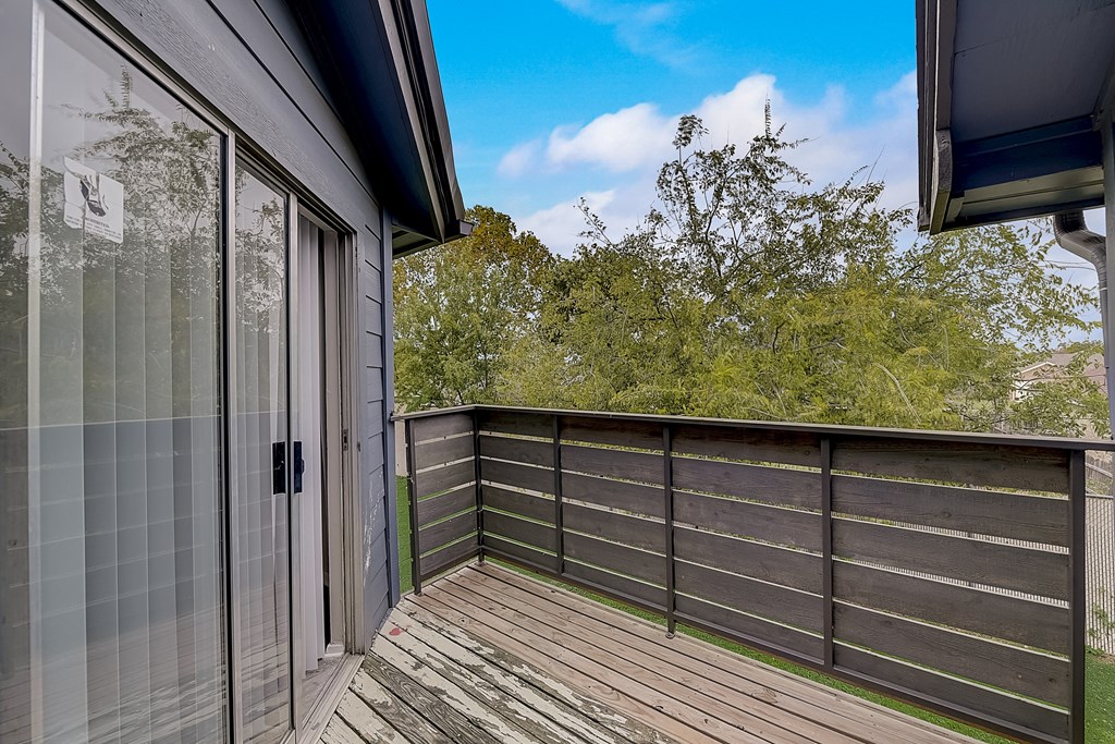 a balcony with a sliding glass door and a wooden deck