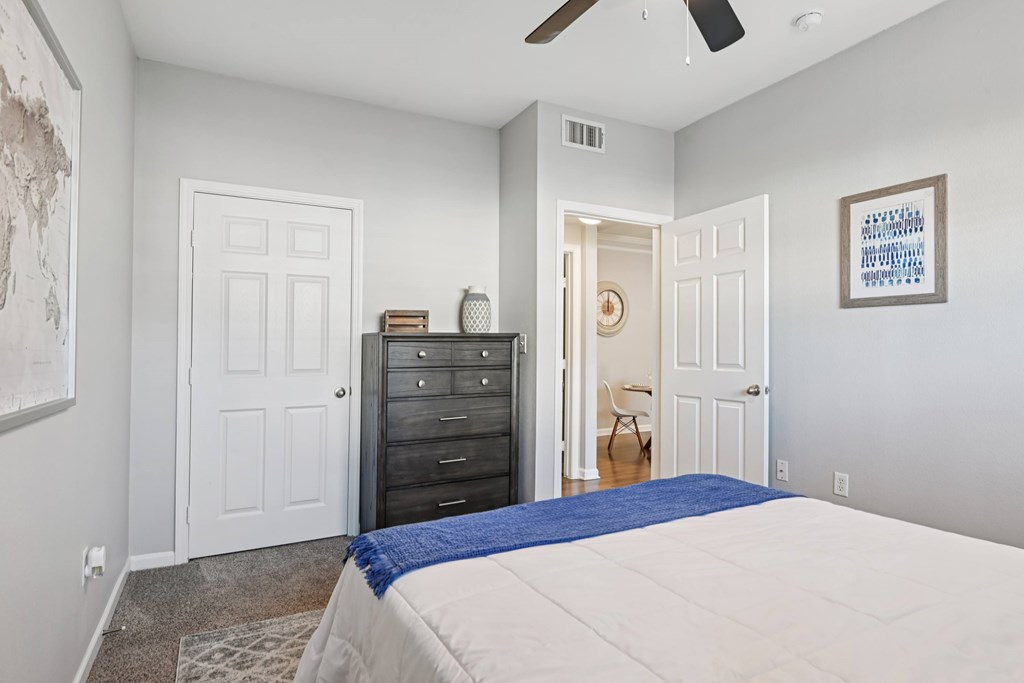 A bedroom with a bed, dresser, and ceiling fan.