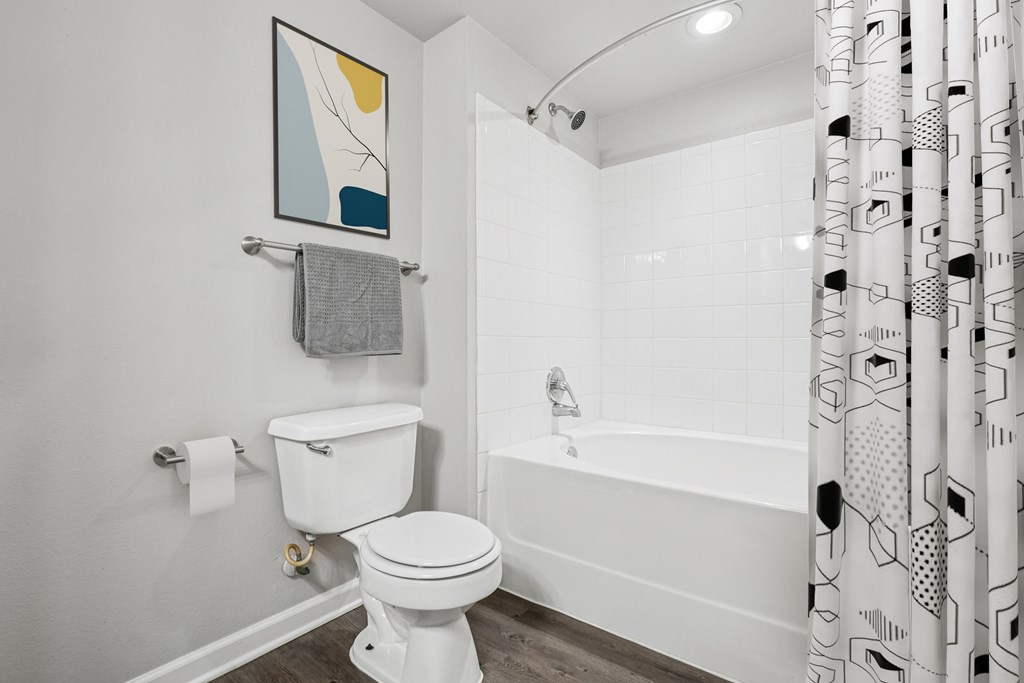 A white toilet is in a bathroom with a patterned shower curtain.