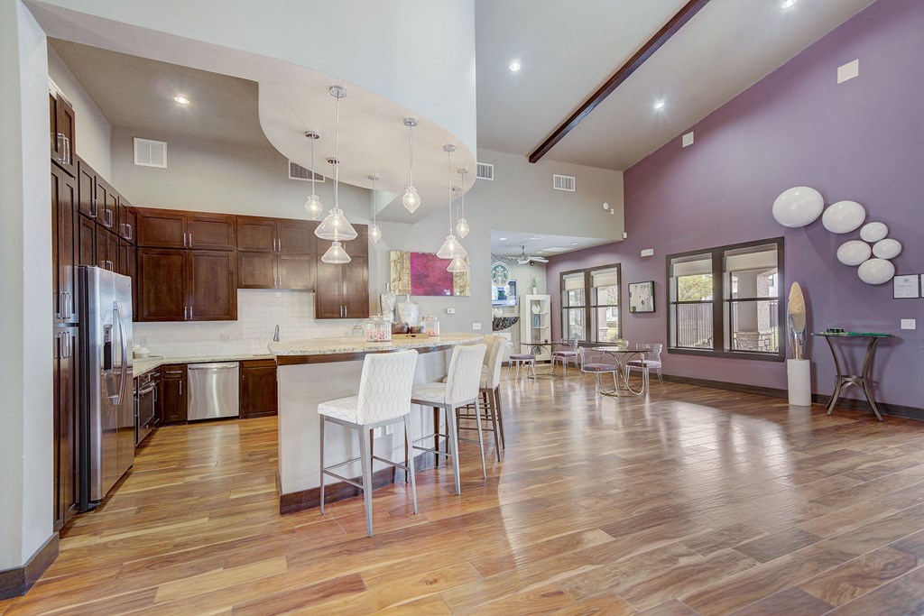 a large kitchen with a dining area and a bar with white chairs