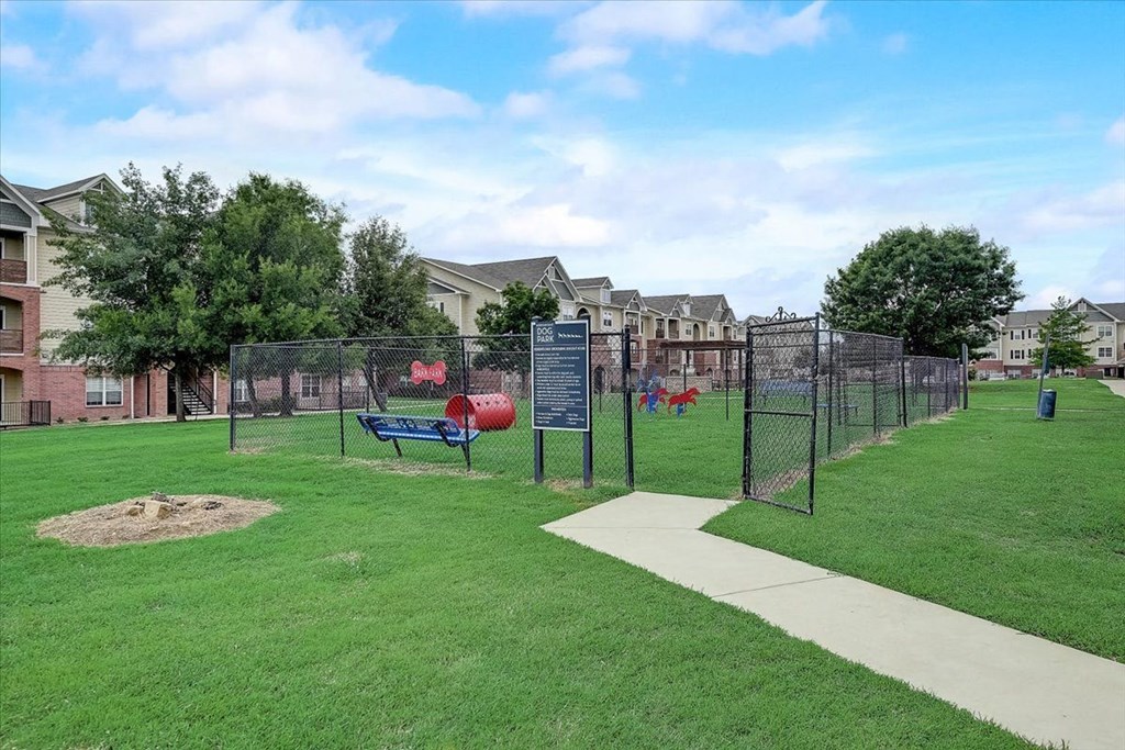 a fenced in park with a playground and houses in the background