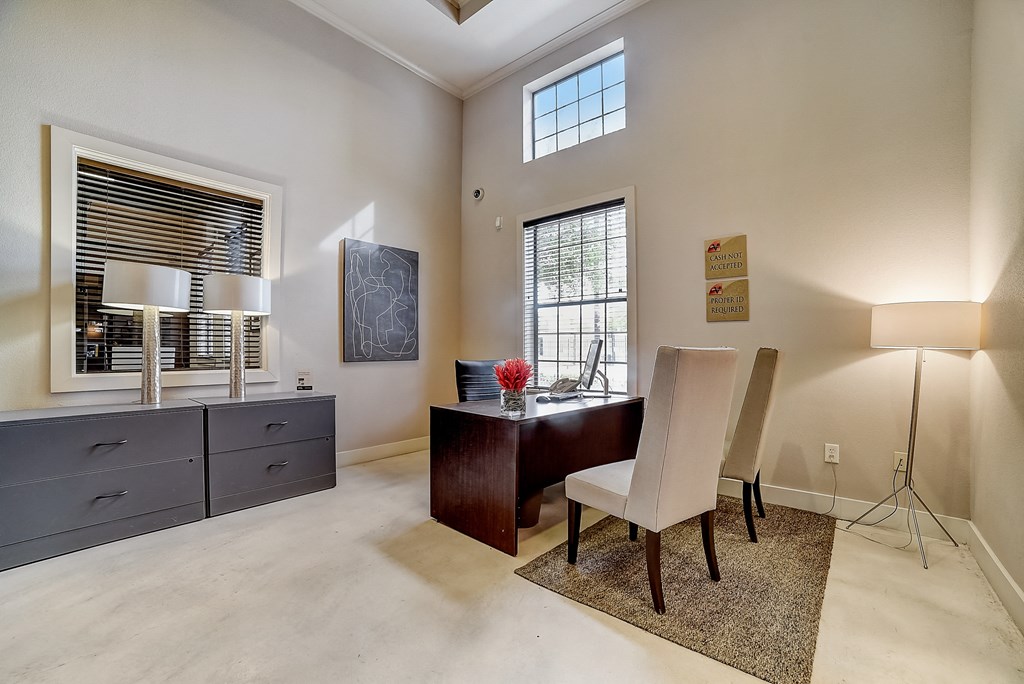 a home office with a dark wood desk and white chairs